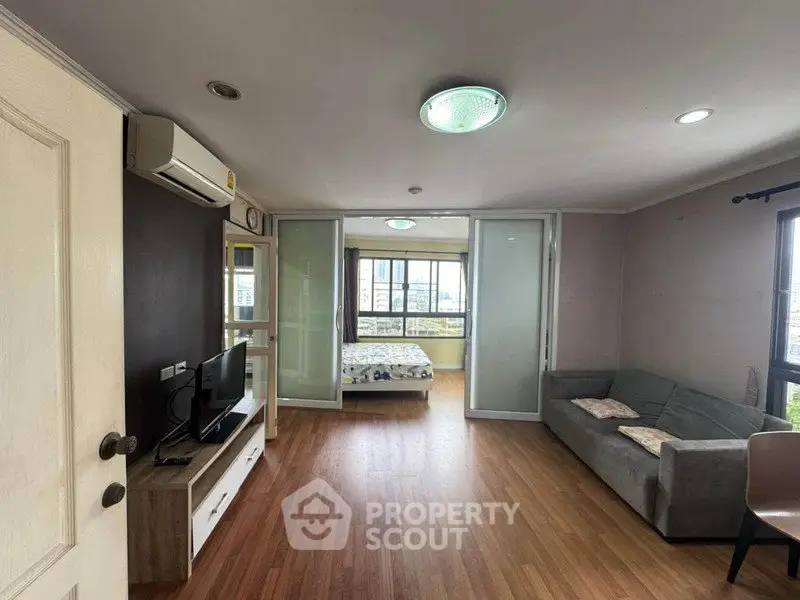 Spacious living room with wooden flooring and modern furnishings in a bright apartment.