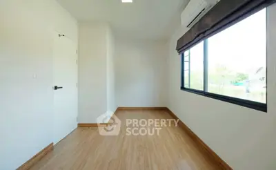 Spacious empty room with wooden flooring and large window