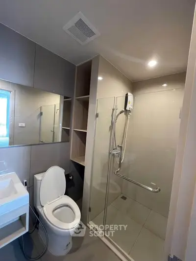 Modern bathroom with glass shower and sleek fixtures in contemporary apartment.