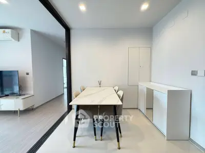 Modern dining area with sleek marble table and stylish chairs in open-plan living space.