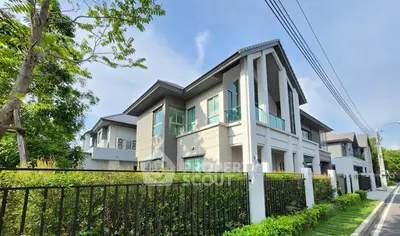 Modern two-story house with lush greenery and sleek architectural design.