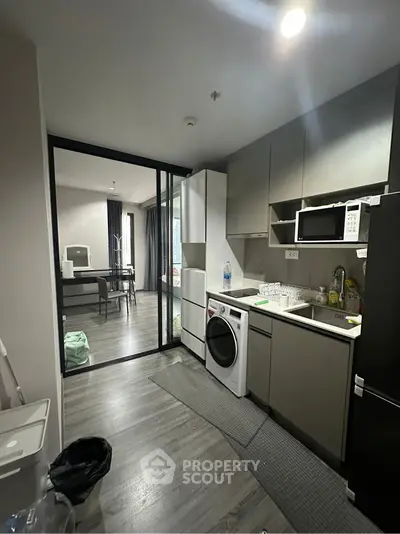 Modern kitchen with sleek appliances and open layout leading to dining area.