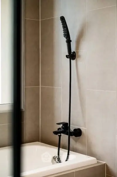 Modern bathroom with sleek black shower fixtures and elegant tiling.
