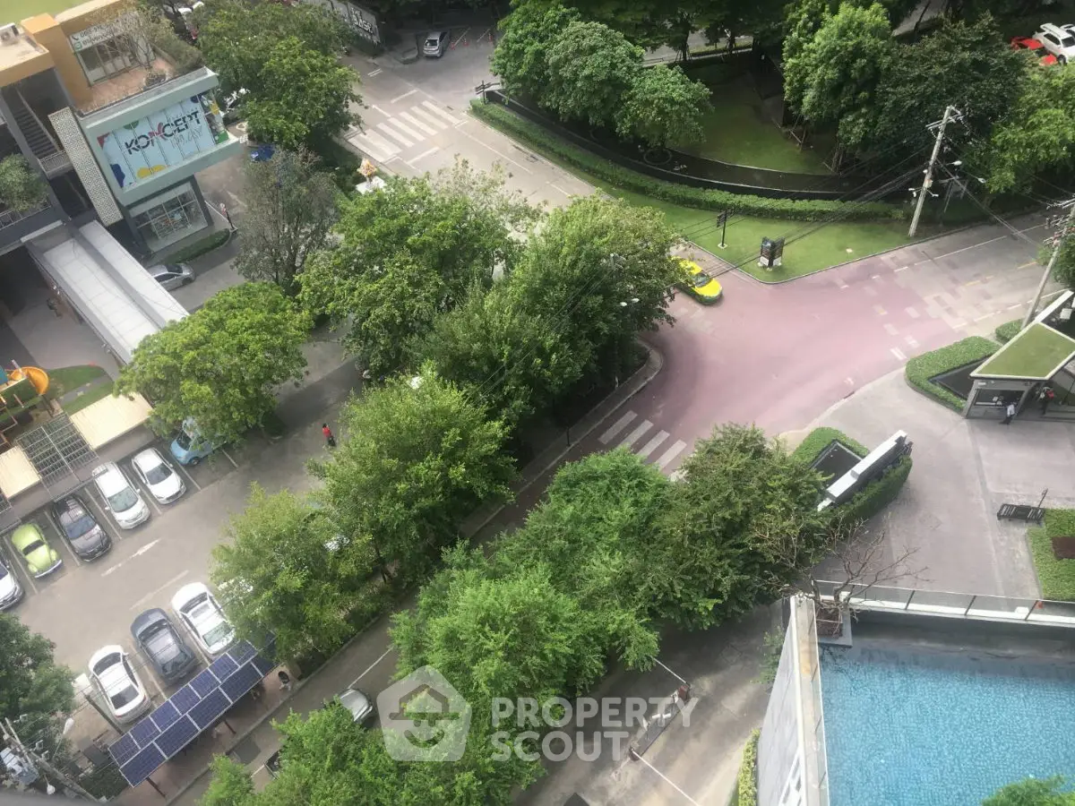 Aerial view of modern residential complex with lush greenery and swimming pool.