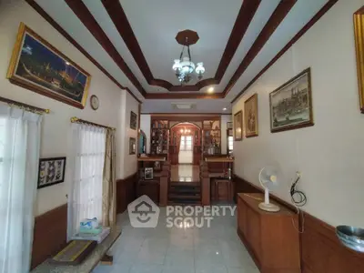 Elegant living room with wooden accents and art-filled walls, featuring a cozy seating area and stylish lighting.