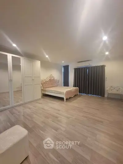 Spacious bedroom with elegant bed and ample closet space, featuring modern lighting and stylish flooring.