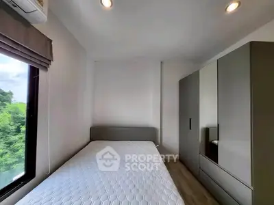 Cozy bedroom with large window and modern wardrobe, offering serene views and ample storage.