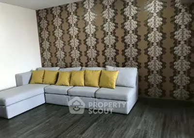 Stylish living room with modern gray sectional sofa and unique patterned wallpaper, perfect for contemporary homes.