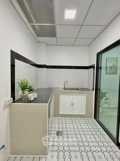 Modern kitchen with sleek design, featuring black and white tiles, stainless steel sink, and ample counter space.
