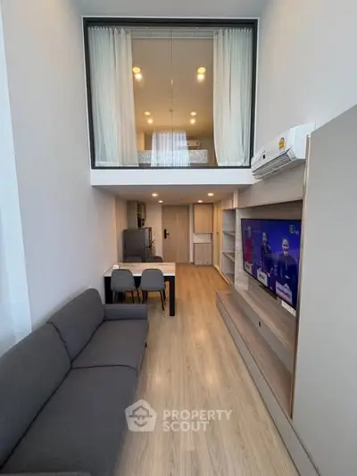 Modern loft apartment with stylish living room and mezzanine bedroom, featuring sleek furniture and open layout.