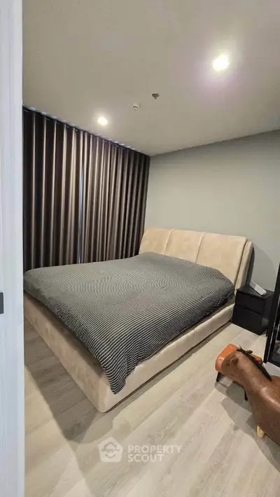 Modern bedroom with stylish bed and floor-to-ceiling curtains in a cozy apartment.