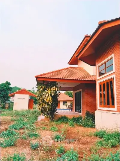 Charming brick house with red roof and lush garden, perfect for serene living.