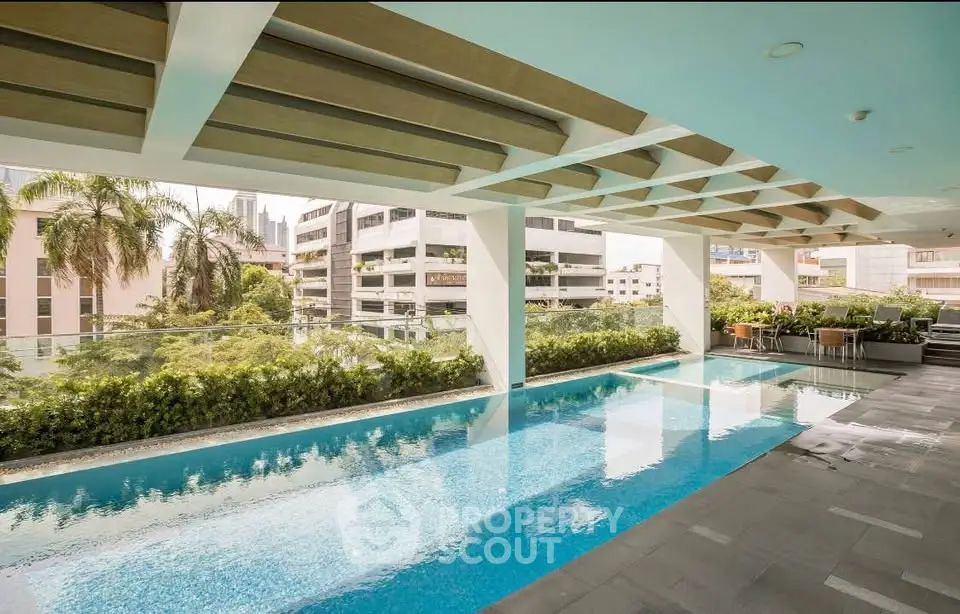 Luxurious rooftop pool with city views and lush greenery in modern apartment complex.