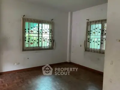 Spacious empty room with parquet flooring and decorative window grills