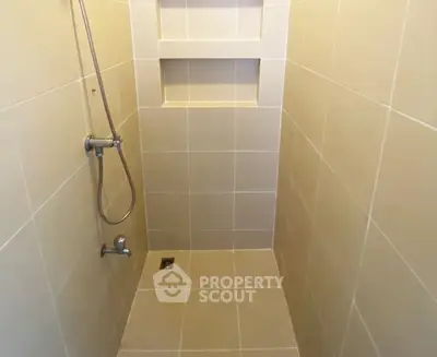 Modern tiled shower area with built-in shelf and handheld showerhead.