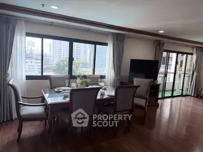 Spacious dining area with elegant furniture and large windows offering city views.