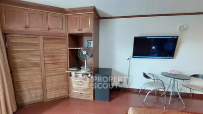Cozy living room with wooden cabinets and wall-mounted TV, ideal for relaxation.