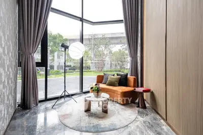Luxurious living room with floor-to-ceiling windows and elegant decor overlooking a serene garden view.