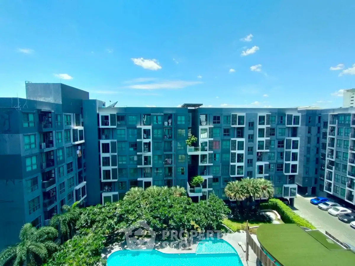 Modern residential building with pool and lush greenery under clear blue sky.