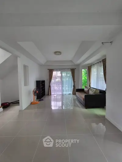 Spacious living room with modern sofa and large windows offering natural light.