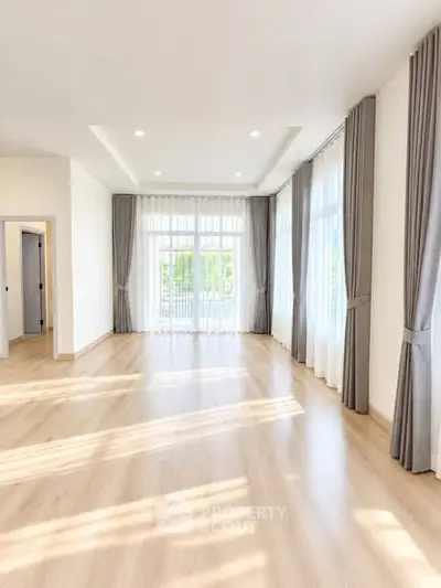 Spacious and bright living room with large windows and elegant curtains, perfect for modern living.