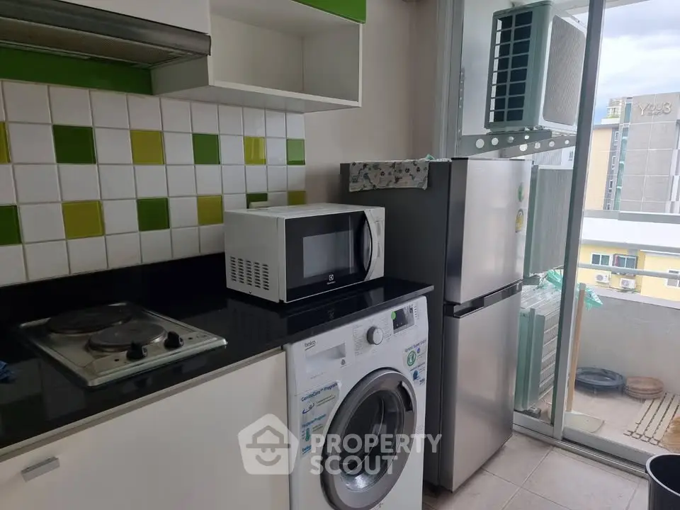 Modern kitchen with appliances including washing machine, microwave, and fridge in a compact layout.