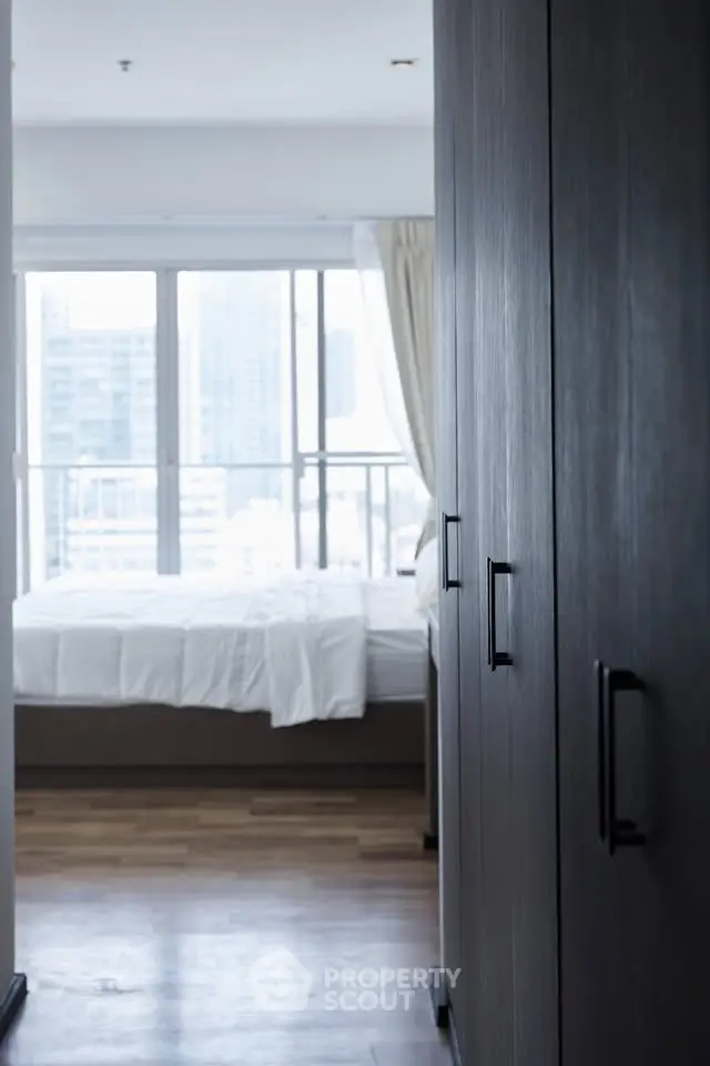 Modern bedroom with large windows and sleek wardrobe in urban apartment