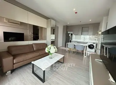 Modern living room with open kitchen, featuring sleek furniture and stylish decor in a contemporary apartment.