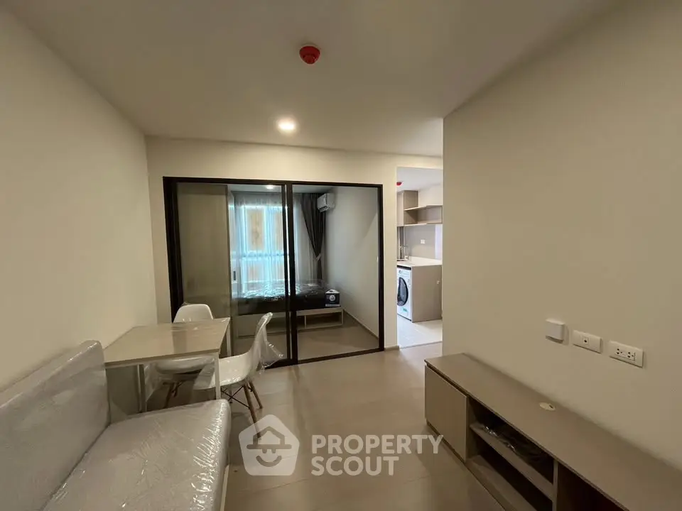 Modern apartment interior with open living area and kitchen, featuring sleek furniture and natural light.