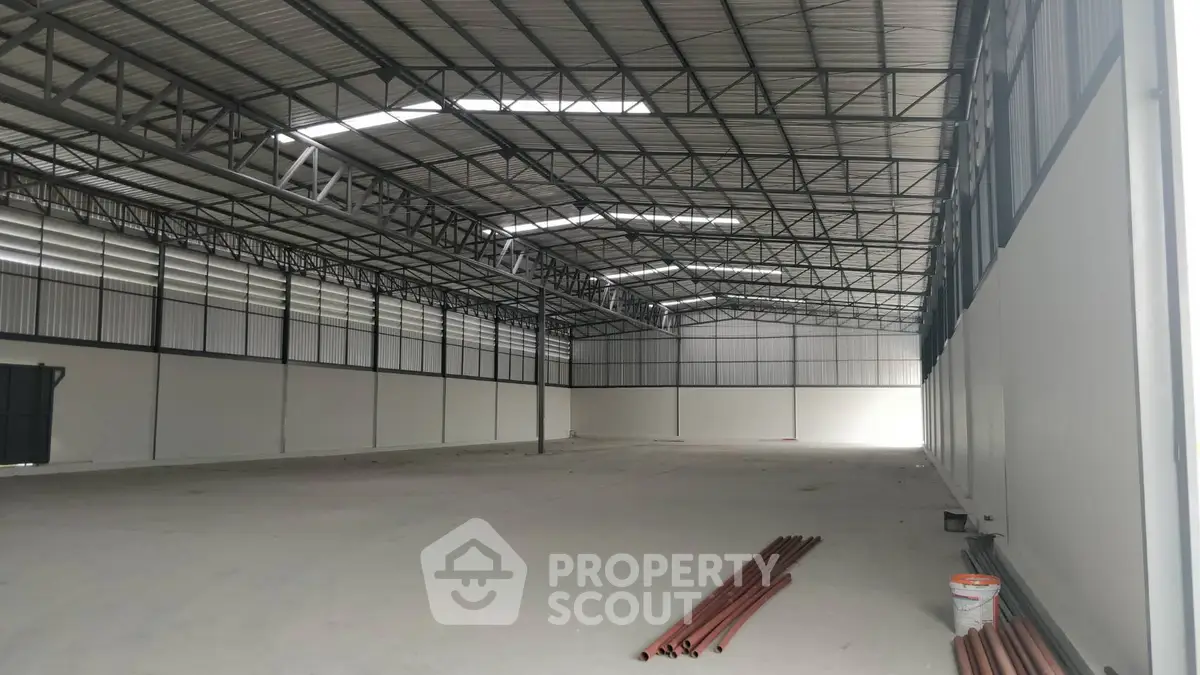 Spacious industrial warehouse with high ceilings and ample natural light, ideal for storage or manufacturing.