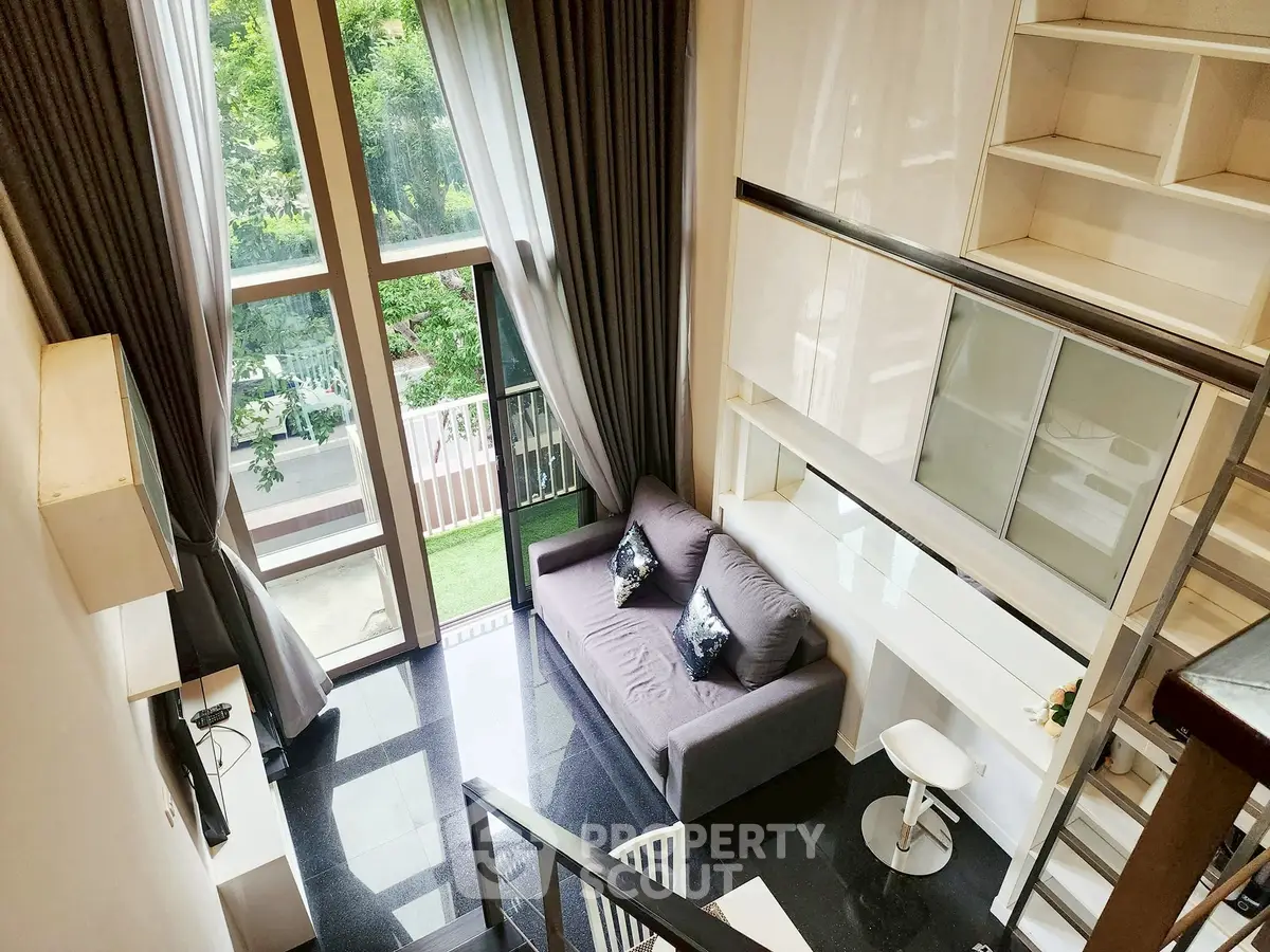 Modern loft apartment with high ceilings and large windows overlooking greenery.