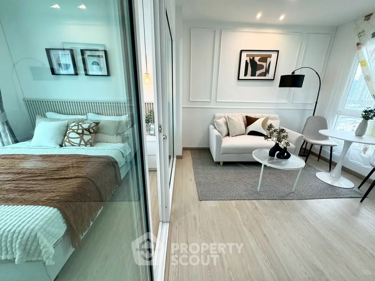Modern studio apartment with stylish living area and cozy bedroom separated by glass partition.