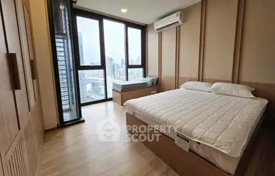 Modern bedroom with city view, featuring large windows and stylish decor.