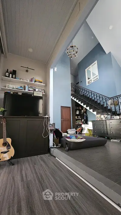 Spacious living room with high ceiling and elegant staircase in modern home