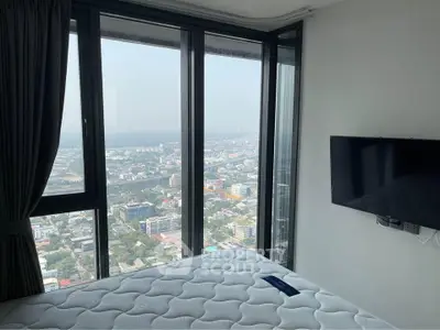 Modern bedroom with panoramic city view and wall-mounted TV