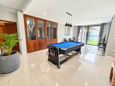 Spacious living room with pool table and garden view, perfect for entertainment and relaxation.