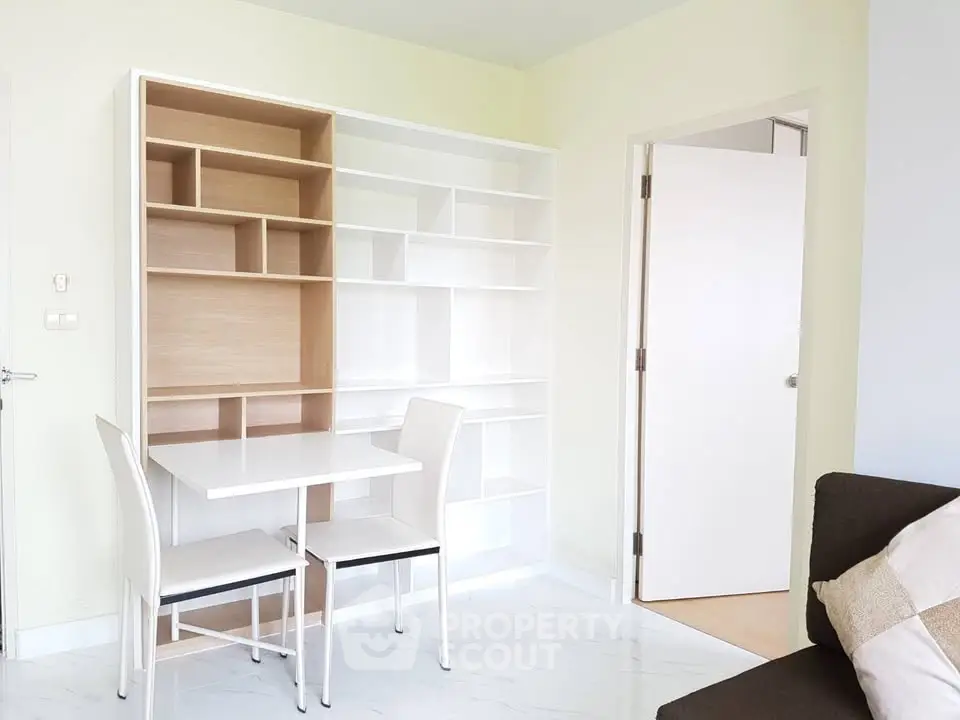 Modern minimalist study room with built-in shelving and sleek white furniture.