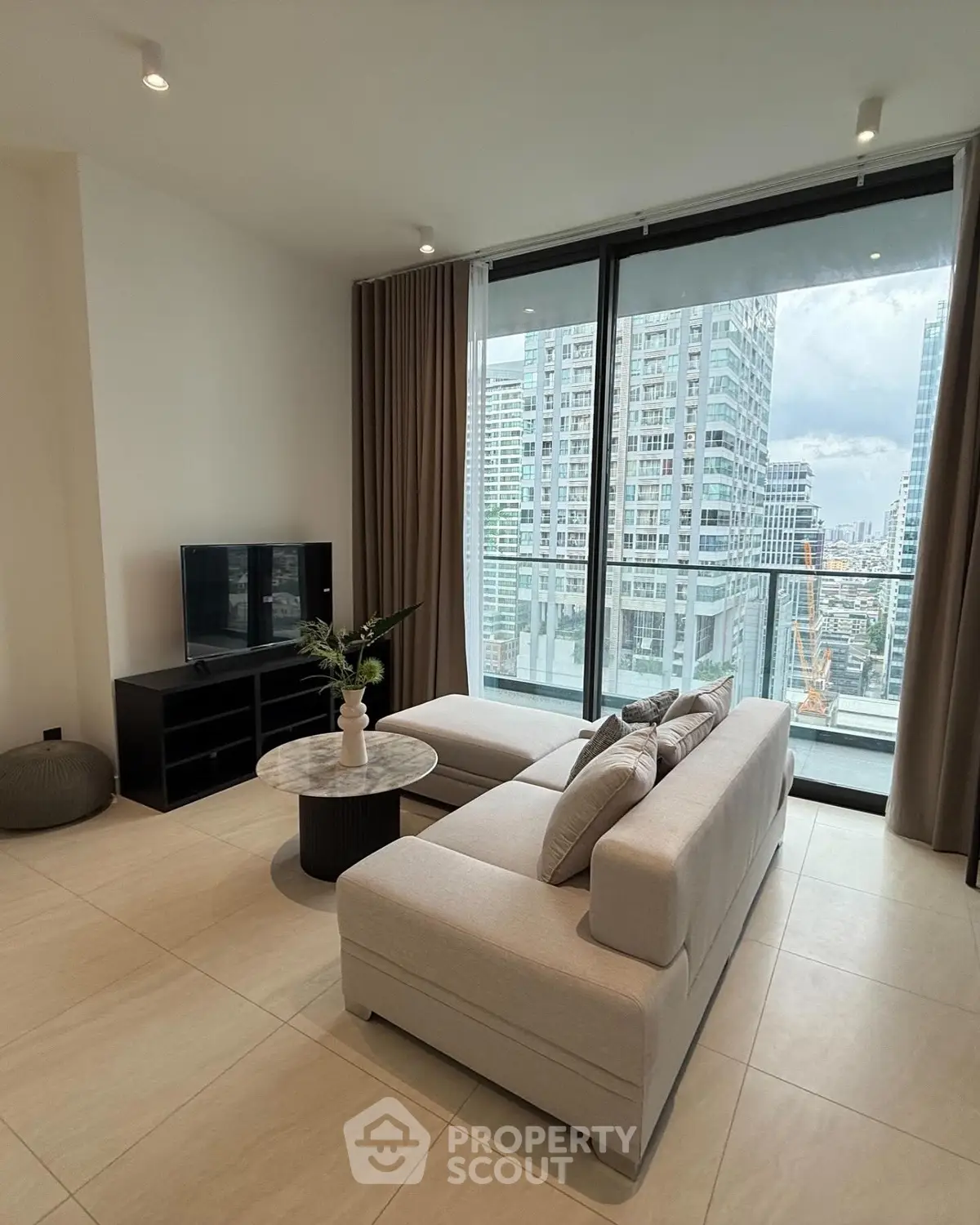 Modern living room with city view, featuring sleek furniture and large windows.