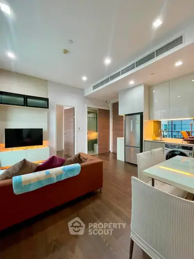 Modern living room with open kitchen, sleek furniture, and bright lighting in a stylish apartment.