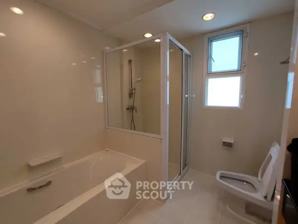 Modern bathroom with bathtub and shower enclosure, featuring sleek fixtures and natural lighting.