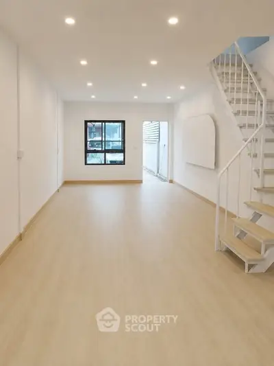 Spacious modern living room with wooden flooring and staircase, perfect for family gatherings.