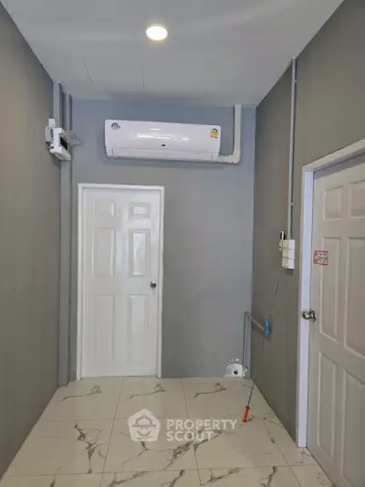 Compact utility room with air conditioning and tiled flooring, ideal for storage or small office space.