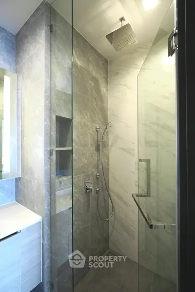 Luxurious modern bathroom with sleek glass shower and elegant marble tiles.