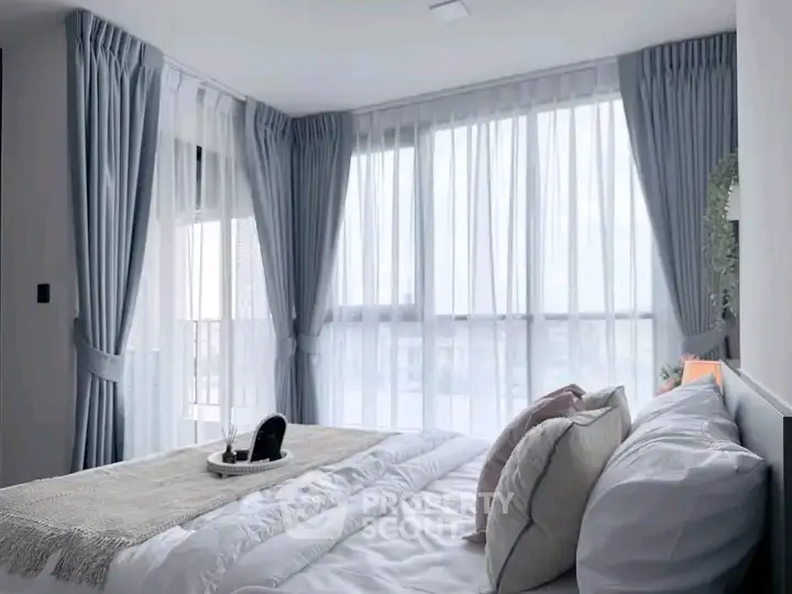 Luxurious bedroom with large windows and elegant curtains, offering a serene and inviting atmosphere.
