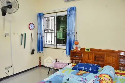 Cozy bedroom with colorful bedding and wall fan, perfect for a comfortable living space.