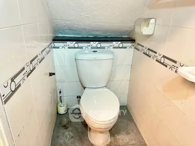 Compact bathroom with sloped ceiling and modern toilet in cozy real estate property.