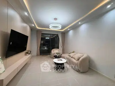 Modern living room with elegant lighting and plush seating, featuring a sleek wall-mounted TV and stylish decor.