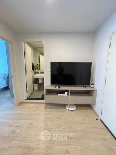Modern living room with TV and glimpse of bathroom, showcasing sleek design and functionality.
