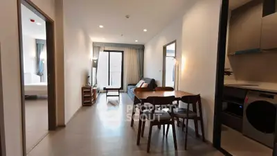 Modern apartment interior with open living and dining area, featuring sleek furniture and natural light.