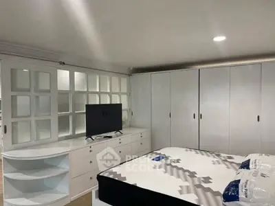 Spacious bedroom with modern furniture and ample storage space, featuring a sleek TV setup.